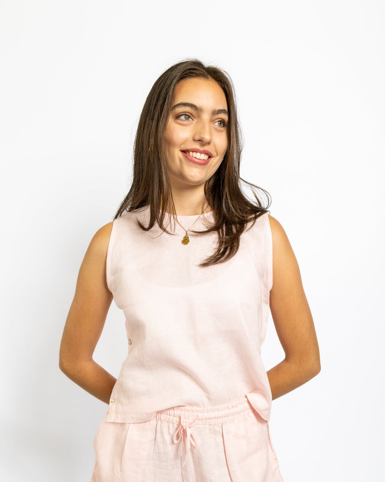 Woman wearing a light pink sleeveless top and shorts set on a white background