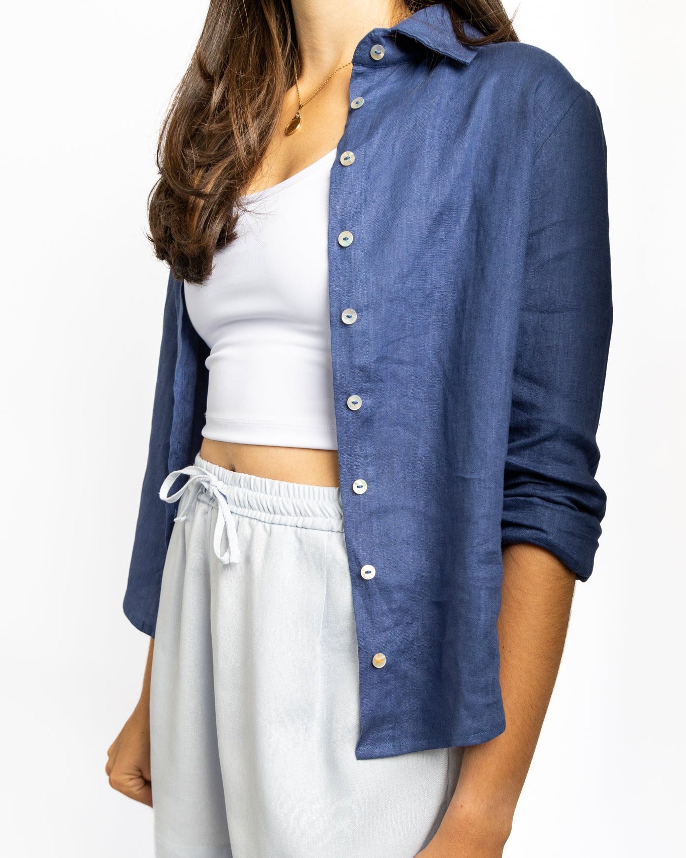 Person wearing a blue shirt over a white top and shorts on a white background