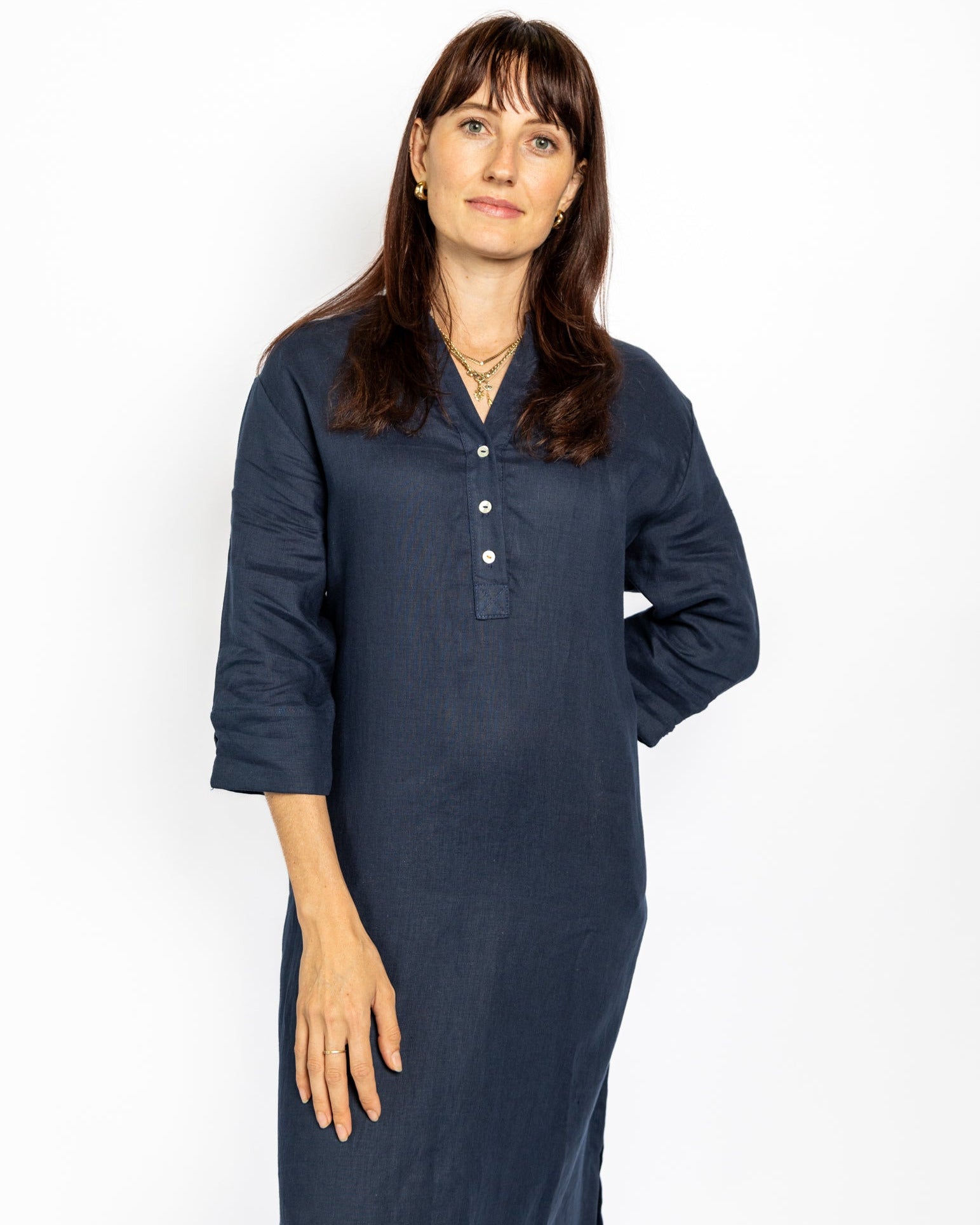 Woman wearing a long navy blue dress against a white background