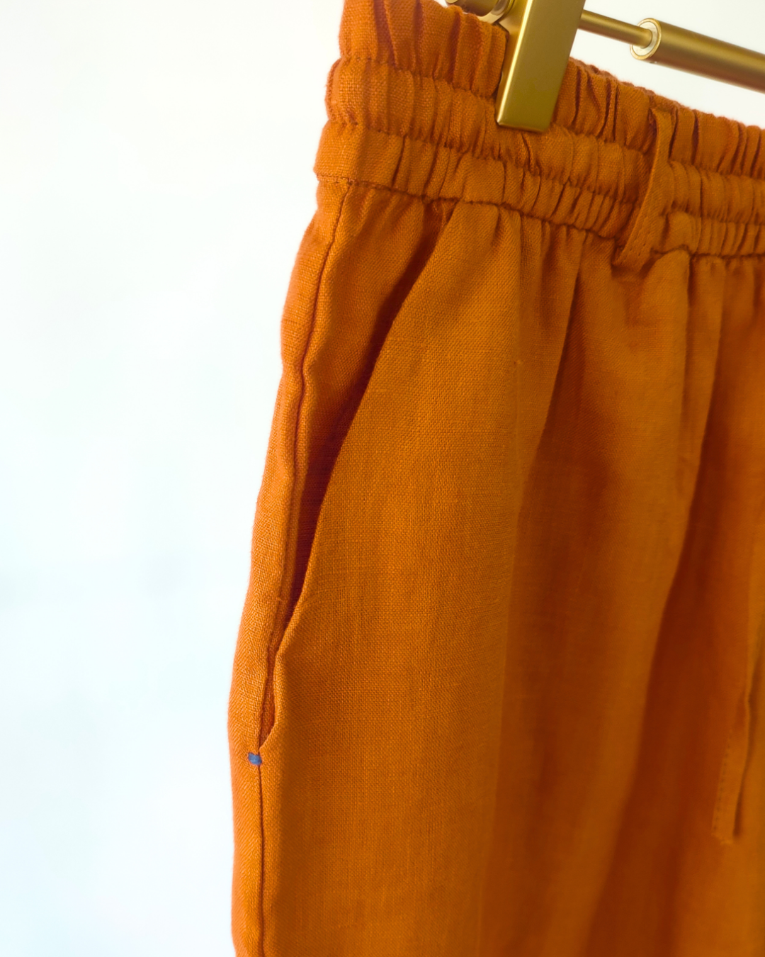 Orange pants on a hanger against a white background